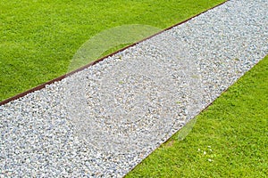 White gravel floor and fresh green lawn with clovers and rusty metal containment profiles