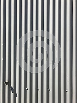 White gray painted corrugated zinc metallic sheet board fence texture pattern on house wall surface background. Detail backdrop