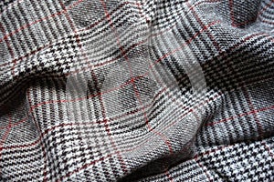 White, gray and red Glen check woolen fabric in soft folds