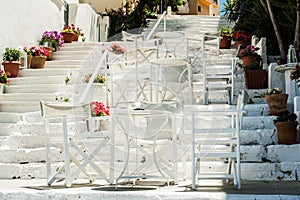 White Greek stairs with tables and chairs. Typical Greek street
