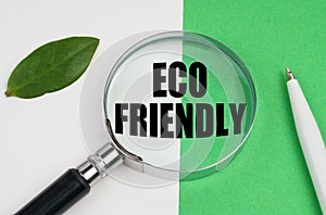 On a white-green background, a pen, a piece of paper and a magnifying glass with the inscription - ECO FRIENDLY