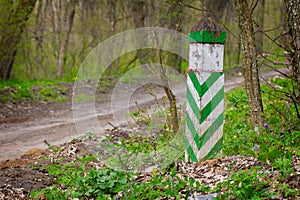 White green boundary post at a spring forest ground road