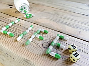 White-green capsules from the jar written the word Life on the table. Next to the dice are two sixes.