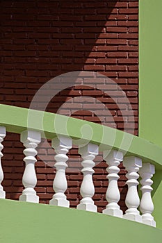 Sunlight and shadow on white and green balustrade with brick wall of vintage balcony