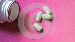 White, green, pink, orange capsules pill spilled out from white plastic bottle container. Global healthcare concept. Antibiotics d