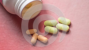 White, green, pink, orange capsules pill spilled out from white plastic bottle container. Global healthcare concept. Antibiotics d