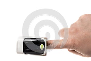 White and green pulse oxymeter on a finger, isolated on white background