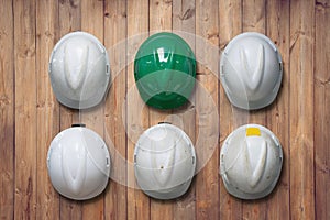 White and green safety hard hat hang on wooden wall