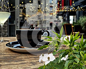white green summer flowers street restaurant black cup of cofee glass of wine and candle light on table top  night street medieva photo