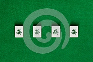 White-green tiles for mahjong on green cloth. 4 dragons