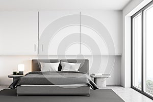 White and grey bedroom, bed with linens near window