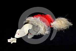 A white and a grey mouse from marshmallow are coming out of a red jelly bag cap in front of black background, sniffling on a star photo