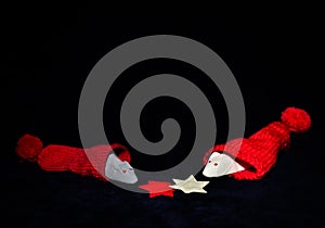 A white and a grey mouse from marshmallow are coming out of a red jelly bag cap in front of black background, sniffling on a star photo