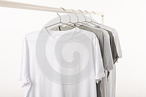 White and grey t shirts on hangers hanging from clothes rail and copy space on white background