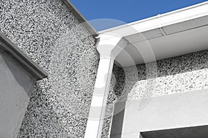 White gutter on the rooftop of house wall rain metal. White plastic rain guttering system. Guttering drainage pipe exterior