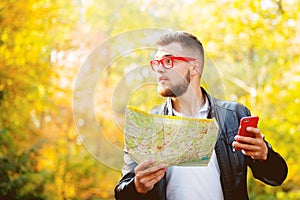 White guy with mobile phone and map in a park