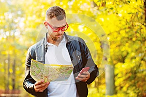 White guy with mobile phone and map in a park