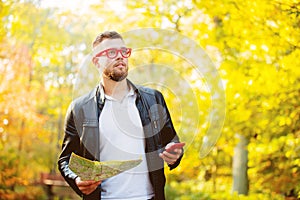 White guy with mobile phone and map in a park