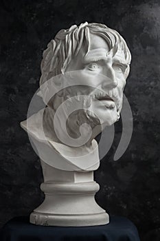 Gypsum copy of ancient statue Seneca head on dark textured background. Plaster sculpture man face.