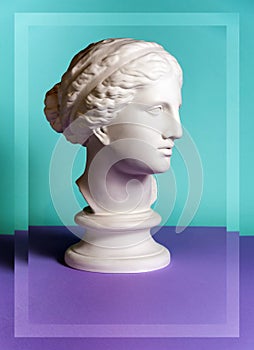 White gypsum copy of ancient statue Venus head on a green purple background. Plaster sculpture woman face.