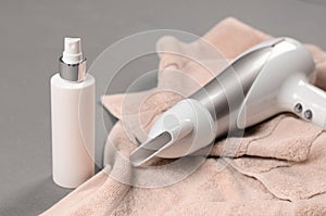 White hair dryer and hairspray on beige towel