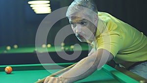 White-haired adult plays snooker. Leisure at the hotel. Face close-up.