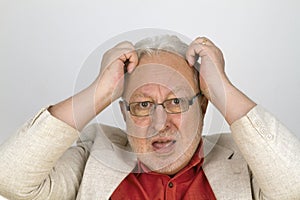 White haired senior with glasses tearing his hair