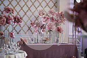 in the white hall of restaurant there are tables with festive decor for a wedding celebration, decoration of the hall with