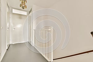 a white hallway with a white railing and a door