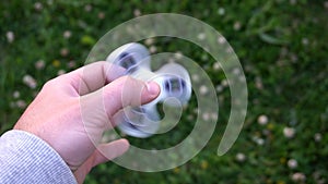 White hand spinner, or fidgeting spinner, rotating on child`s hand