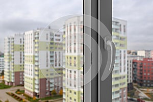 A white handle of a closed plastic window