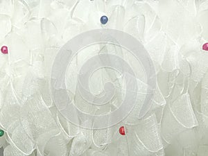 White handmade airy chiffon tulle ribbons curled soft organza fabric with color beads. Texture background