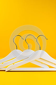 White hangers on a yellow background. Sales clothes concept