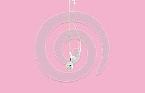 White hanging ear buds headphones isolated on a pink background