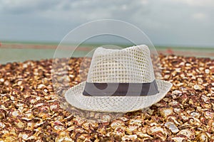 White hat lies on a shell stone beach on a blurred background of blue sea