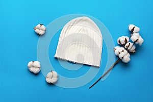 A white hat and sprigs of cotton on a blue background