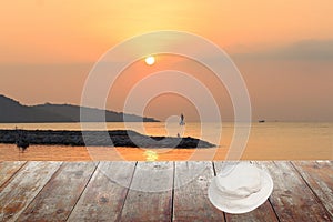 White hat on wood table in morning sunrise at sea