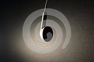White earphone with brown light on dark background