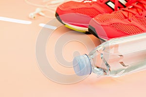 White headphones, a bottle of fresh water and pink sneakers