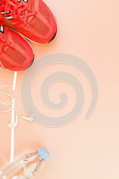 White headphones, a bottle of fresh water and pink sneakers