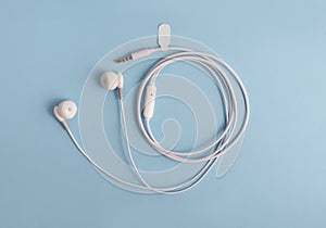 White headphones with a label on a blue background. Music concept. Copy space