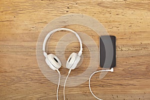 White headphones and smart phone on wood