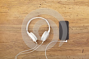 White headphones and smart phone on wood