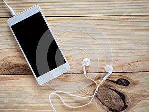 White headphones with smartphones on the wood table and free space for text and logo or symbols