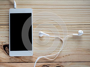 White headphones with smartphones on the wood table and free space for text and logo or symbols