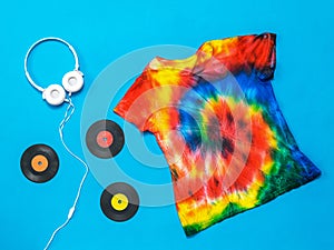 White headphones, vinyl discs and a tie dye t-shirt on a blue background. Flat lay. Pastel color.
