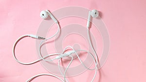 White headphones with wires on a pink background