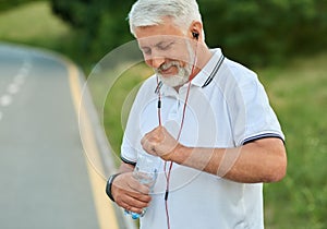 White-heared senior man opening water bottle during morning scamper.