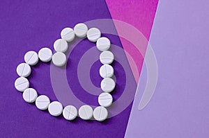 White heart pills on a colored background.
