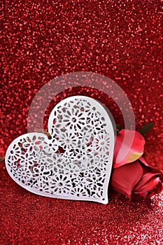 White heart and rose on red glitter background